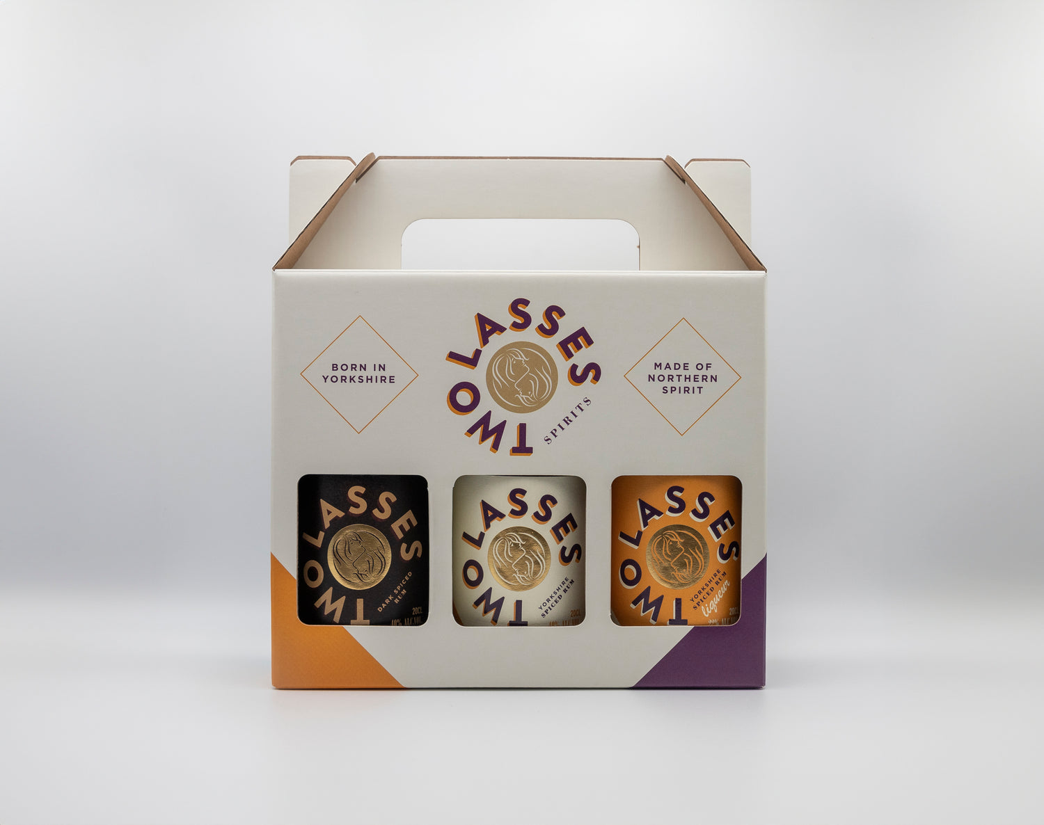 Three-bottle Two Lasses Spirits gift box with Yorkshire Spiced, Dark Spiced, and Liqueur bottles in a branded carrier.